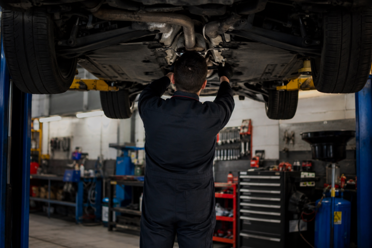 Auto su ponte elevatore in officina con meccanico